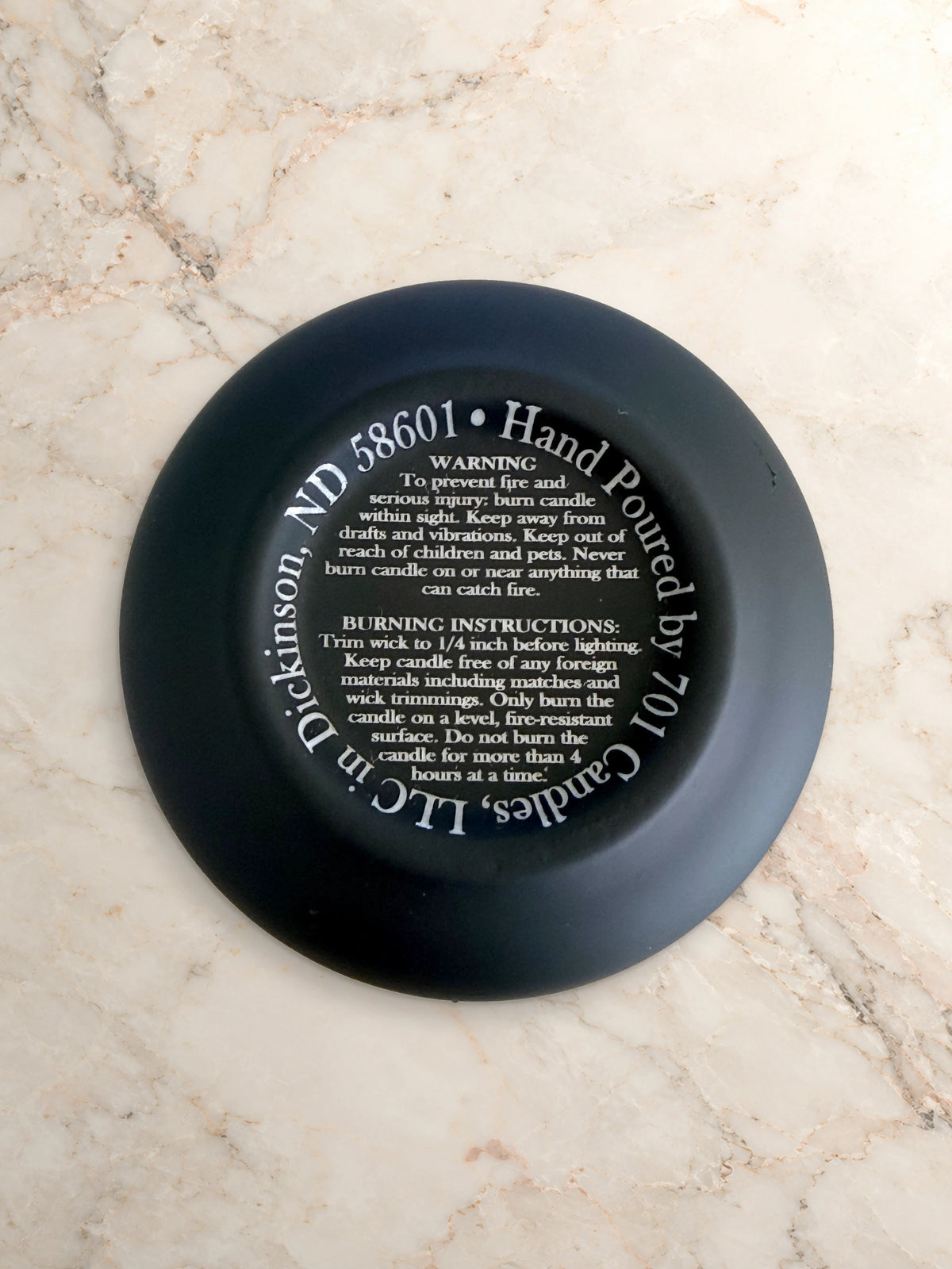 701 Candles base with engraved warning and candle burning instructions on warm marble