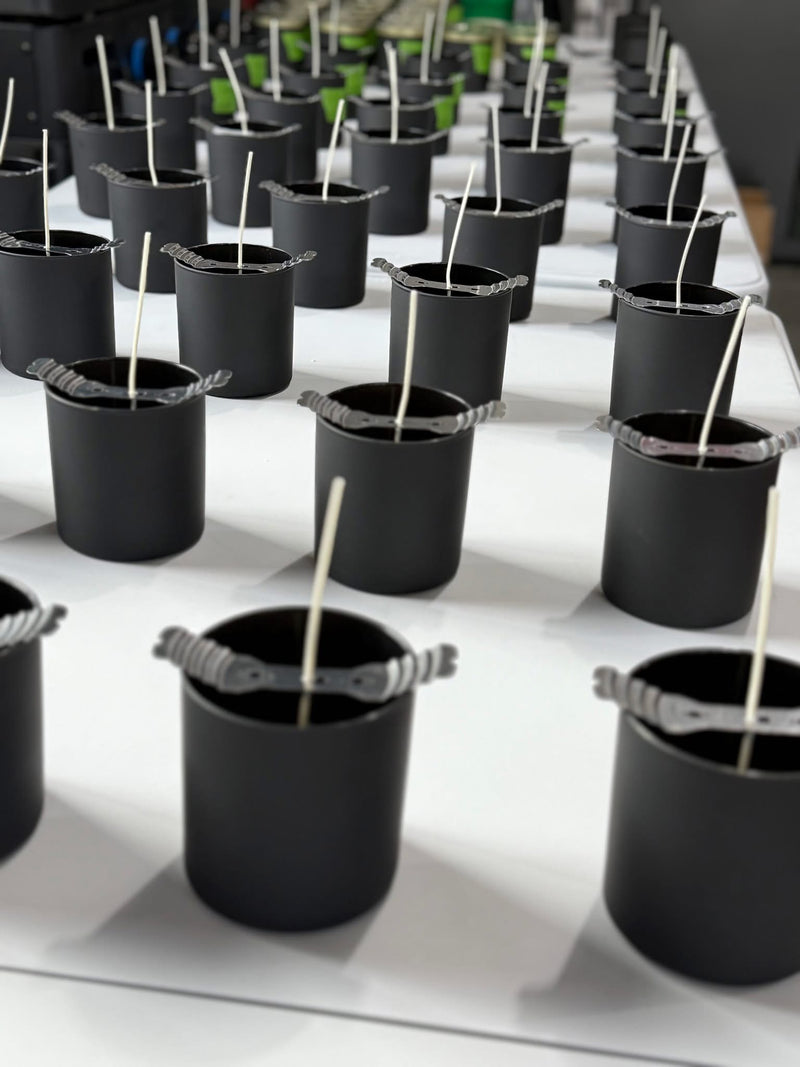 Matte-black candle vessels and centered wicks in the 701 Candles workshop